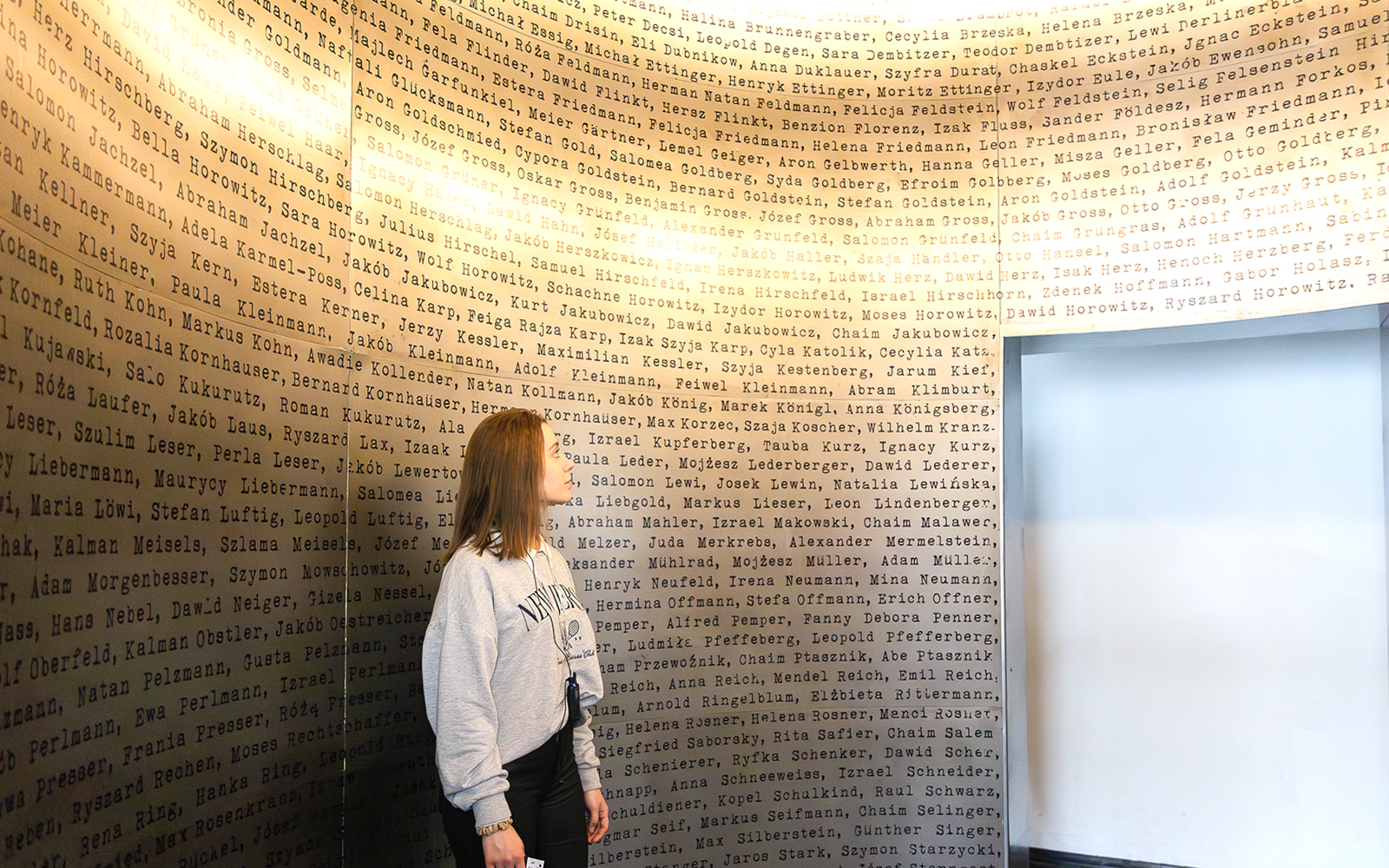 Woman observing names on a wall inside Oskar Schindler's Factory, Krakow.