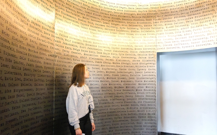 Woman observing names on a wall inside Oskar Schindler's Factory, Krakow.