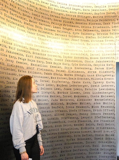 Woman observing names on a wall inside Oskar Schindler's Factory, Krakow.