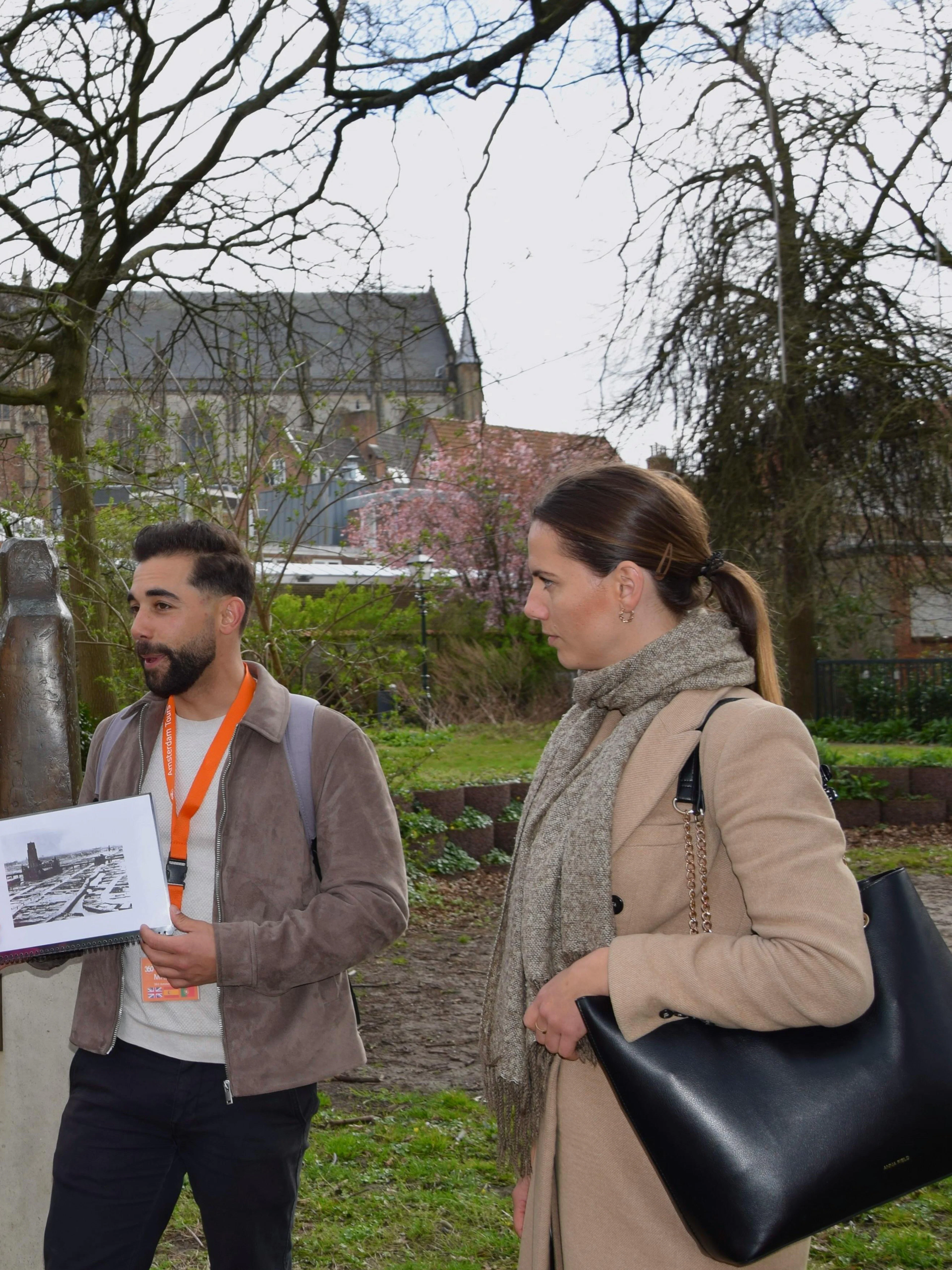 Tour guide explaining WWII history to group in Haarlem park near statue.