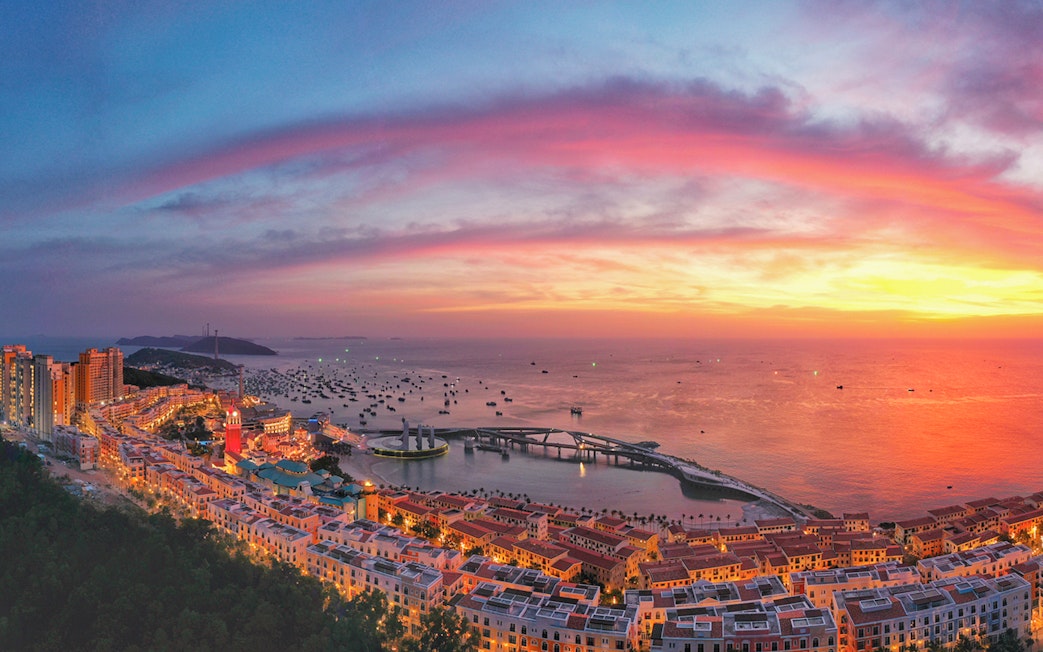 Sunset view of the world's longest sea-crossing cable car over ocean and islands.