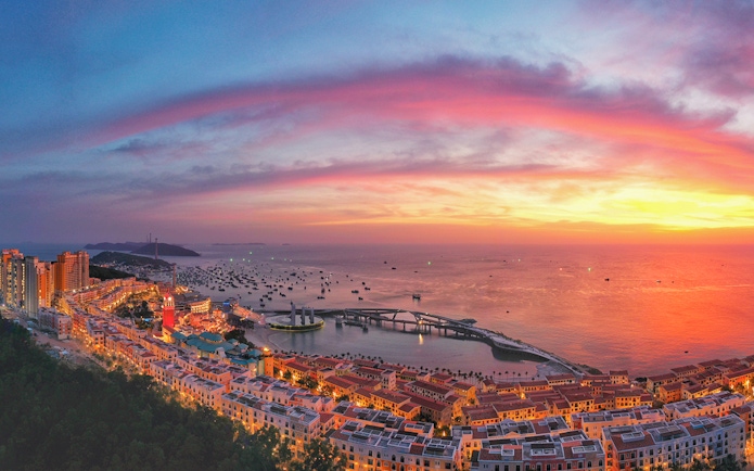 Sunset view of the world's longest sea-crossing cable car over ocean and islands.