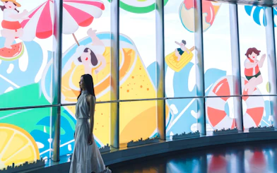 Visitor at the Top of Shanghai observation deck with colorful mural in Shanghai Tower.