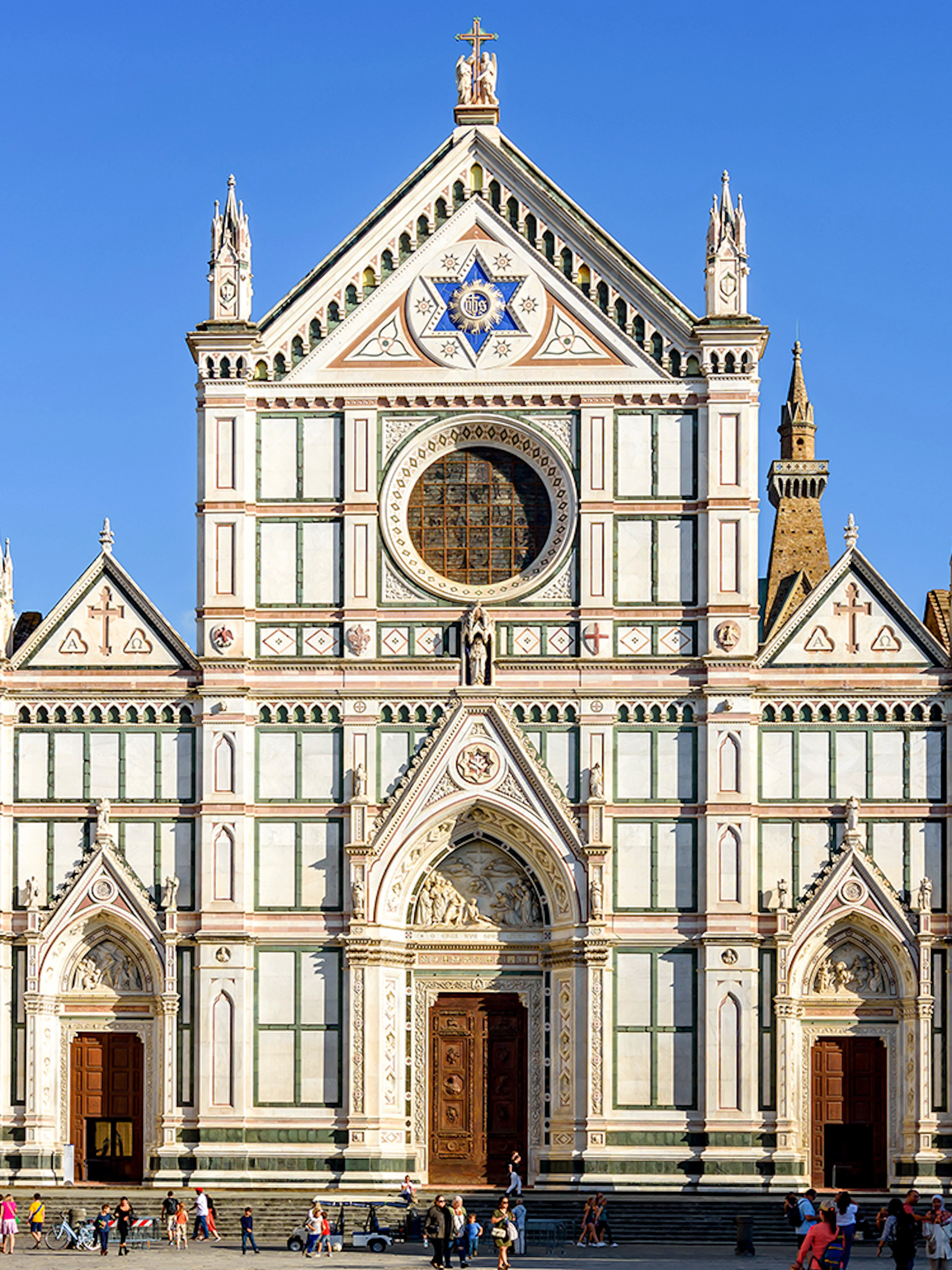Santa Croce Basilica facade in Florence, Italy, with tourists exploring the square.