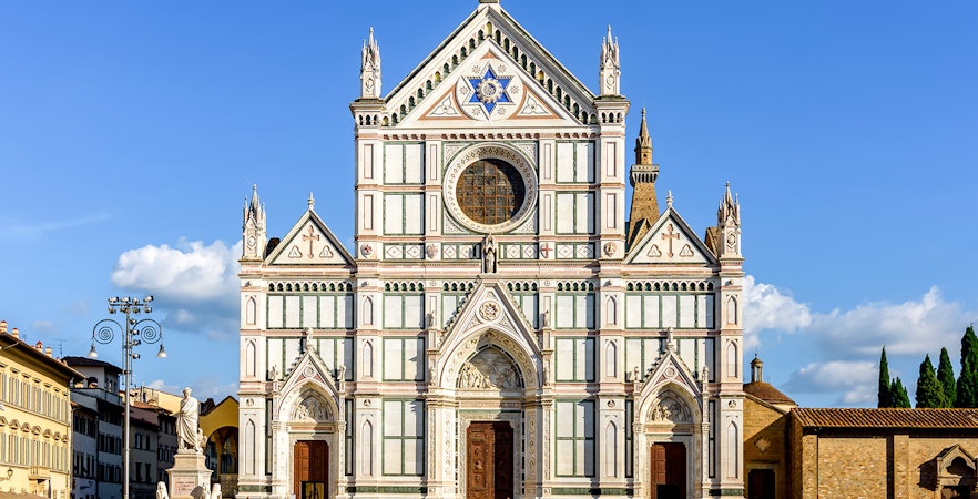 Santa Croce Basilica facade in Florence, Italy, with tourists exploring the square.