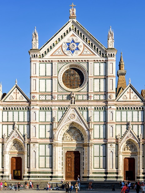 Santa Croce Basilica facade in Florence, Italy, with tourists exploring the square.