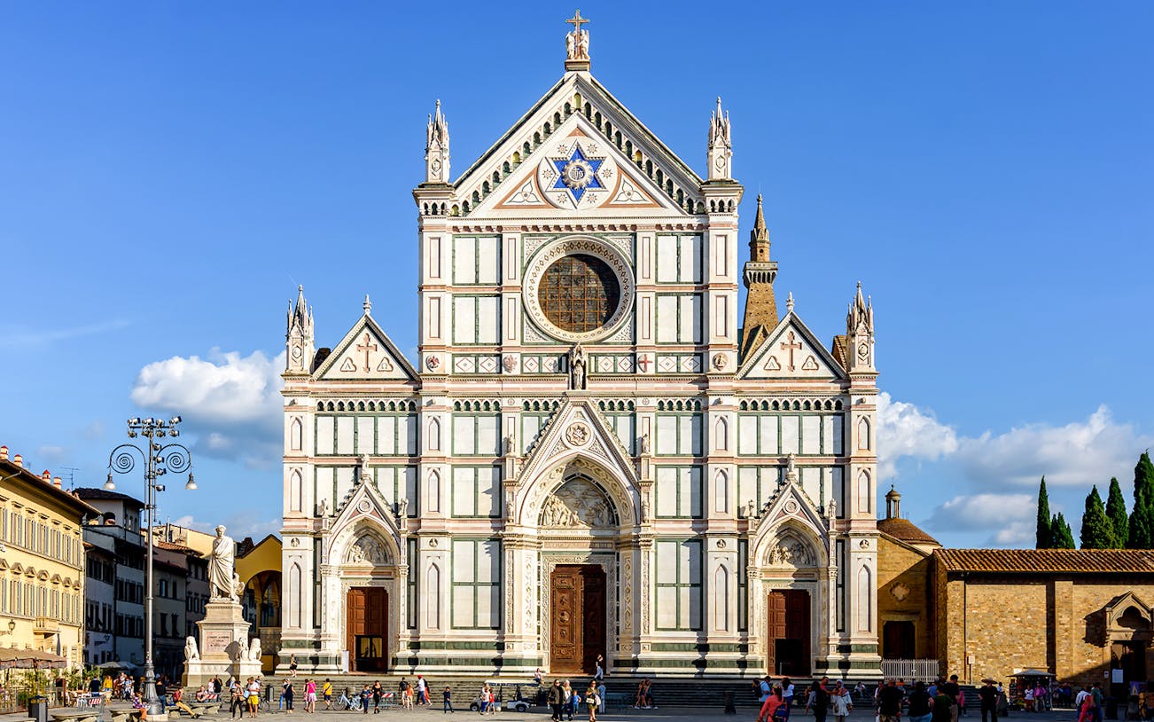 Santa Croce Basilica facade in Florence, Italy, with tourists exploring the square.