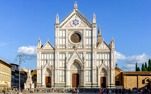 Santa Croce Basilica facade in Florence, Italy, with tourists exploring the square.