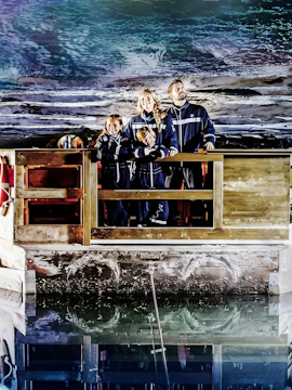 Family exploring Berchtesgaden Salt Mine in Bavaria, standing on a wooden platform.