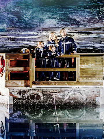 Family exploring Berchtesgaden Salt Mine in Bavaria, standing on a wooden platform.