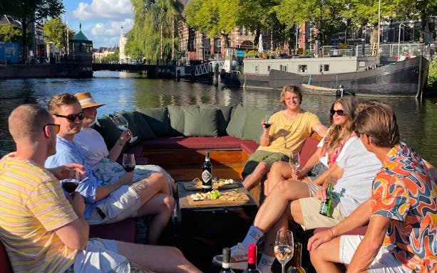 Group enjoying wine on a boat during Groningen historical canal cruise.