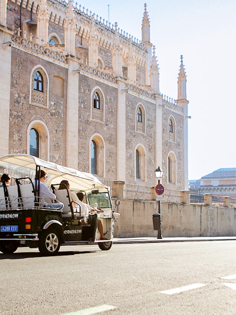 Eco Tuk Tuk tour passing historic building in Madrid.