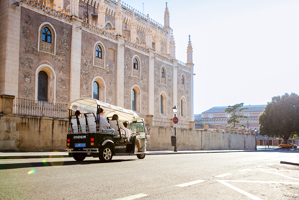 Eco Tuk Tuk tour passing historic building in Madrid.