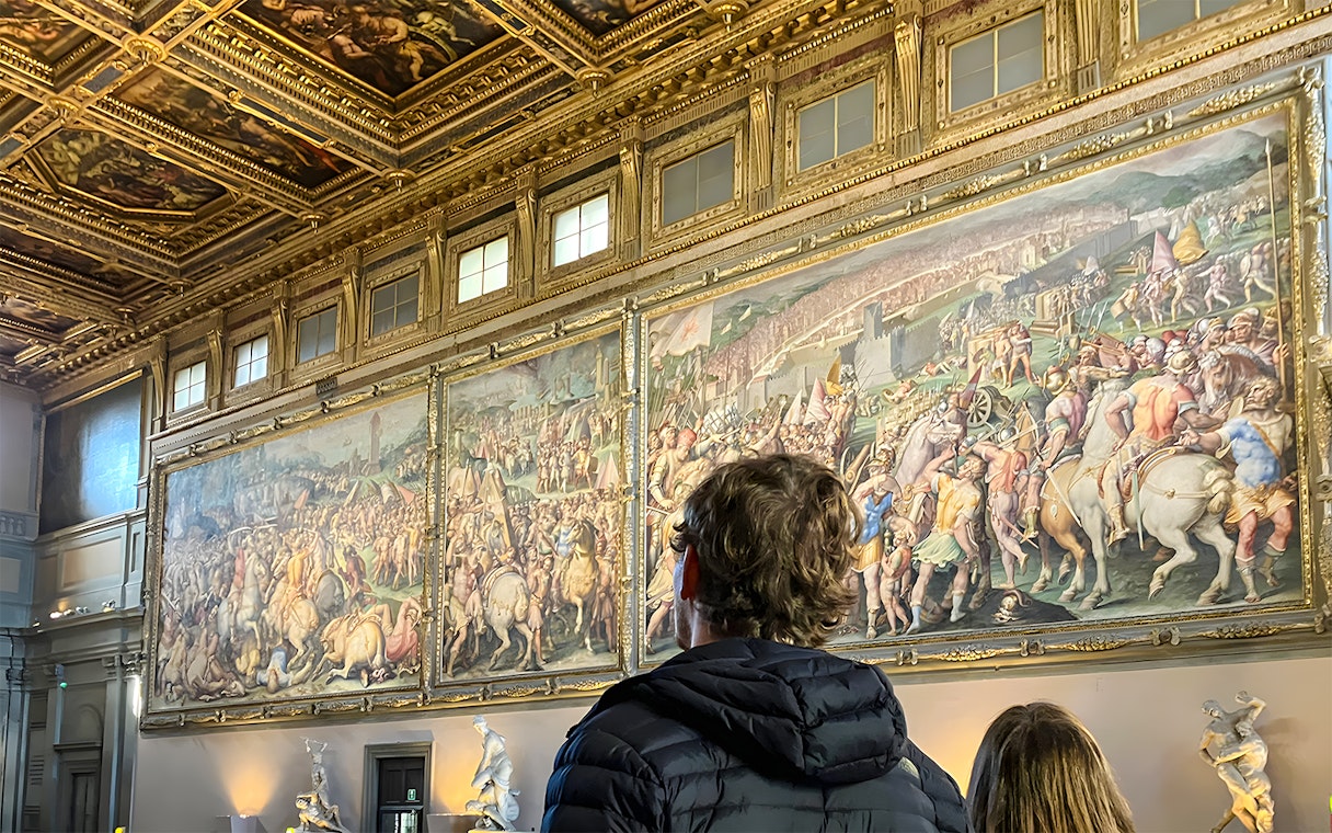Tourists viewing frescoes inside Palazzo Vecchio, Florence.
