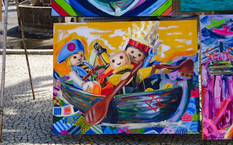 Colorful painting of toy figures rowing a boat at Ipanema Street Market, Rio de Janeiro.