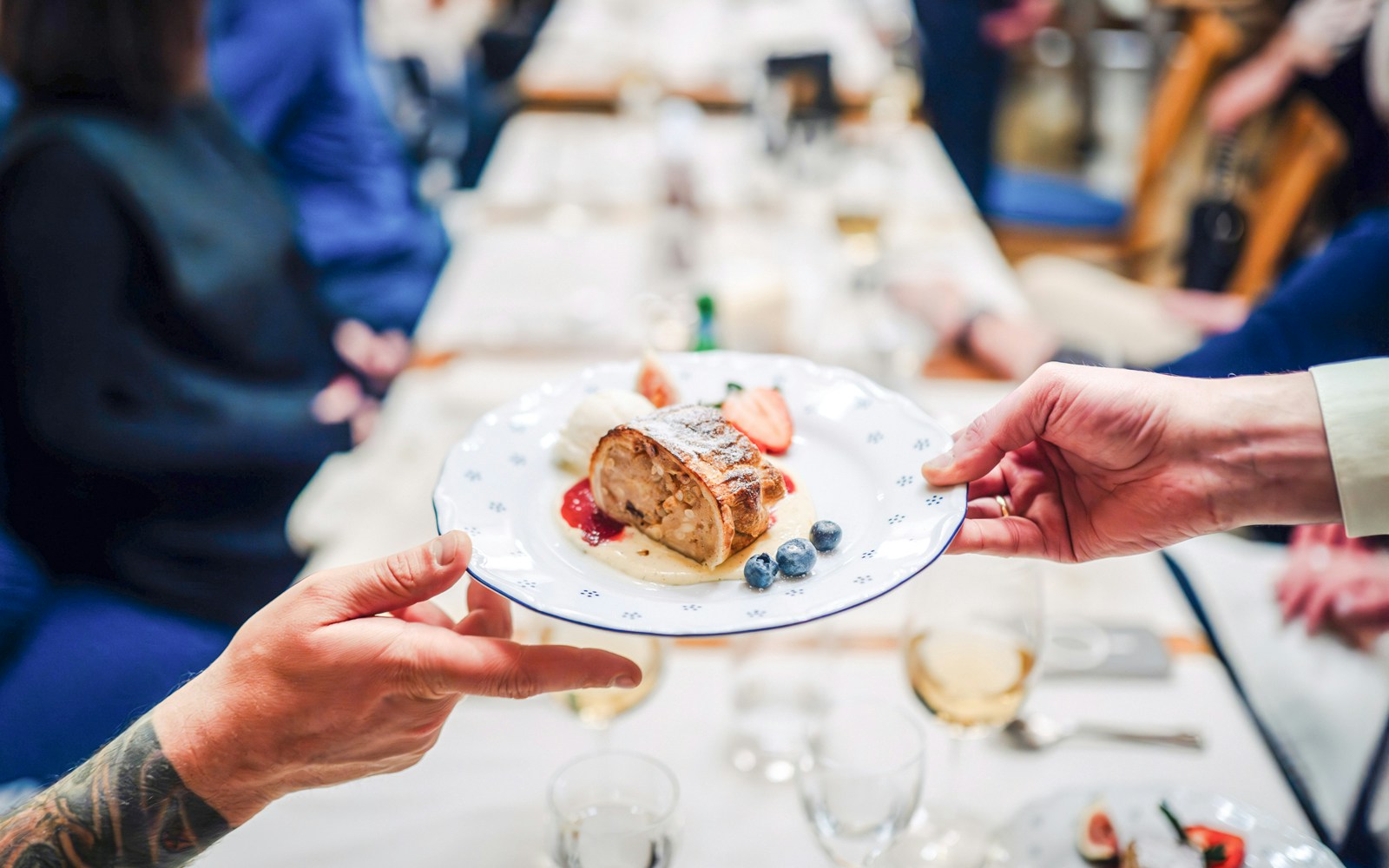 Plate of apple strudel with berries being shared by two people at a dining table.