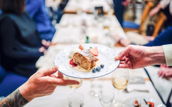 Plate of apple strudel with berries being shared by two people at a dining table.