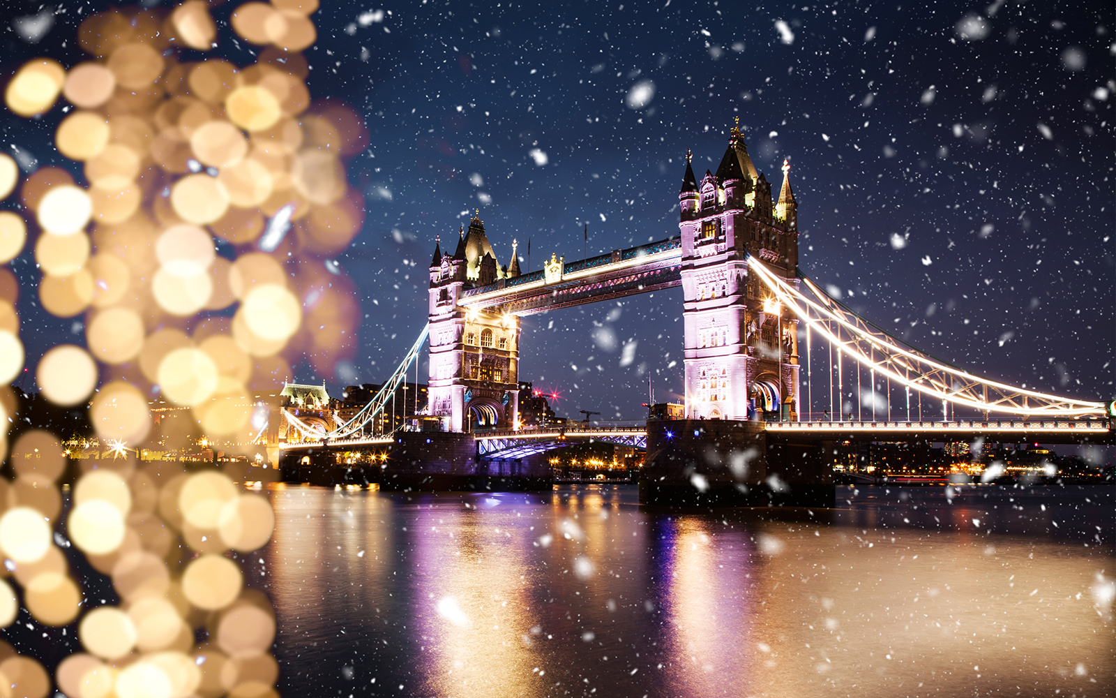 Tower Bridge illuminated at night with snow falling, London in January.