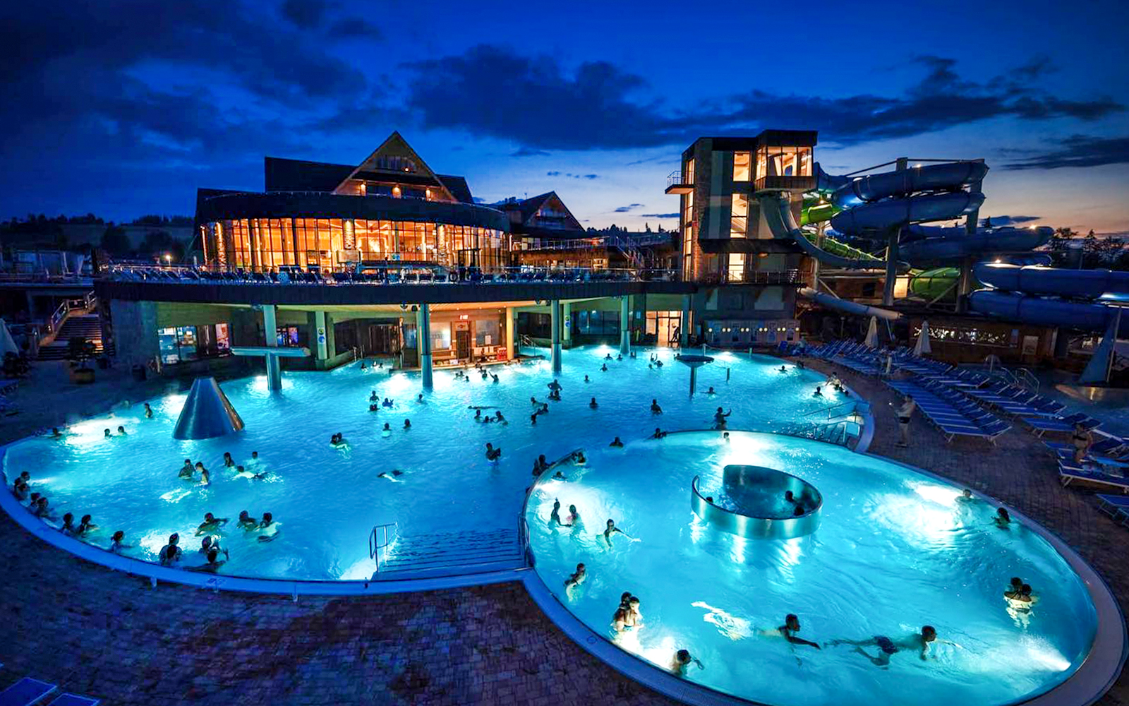 Zakopane Thermal Baths at night with illuminated pools and water slides.