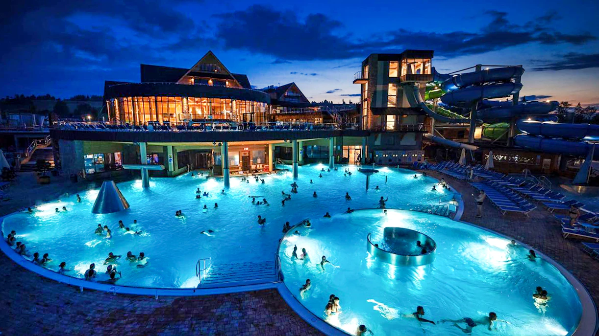 Zakopane Thermal Baths at night with illuminated pools and water slides.