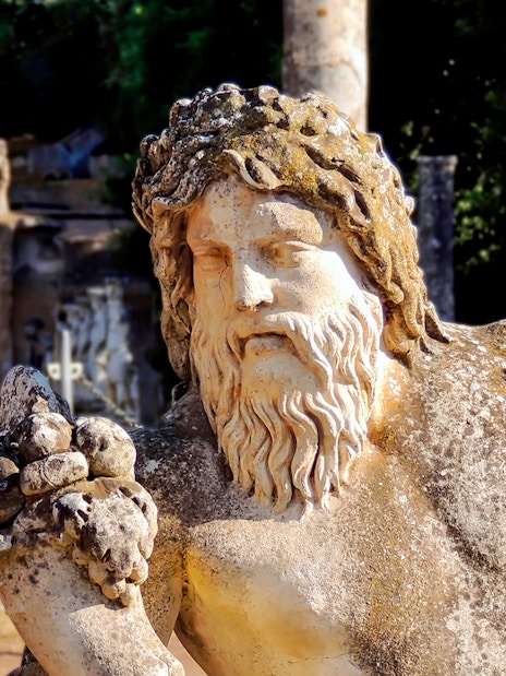 Statues at Villa Adriana, Tivoli, with ancient columns and water in the background.