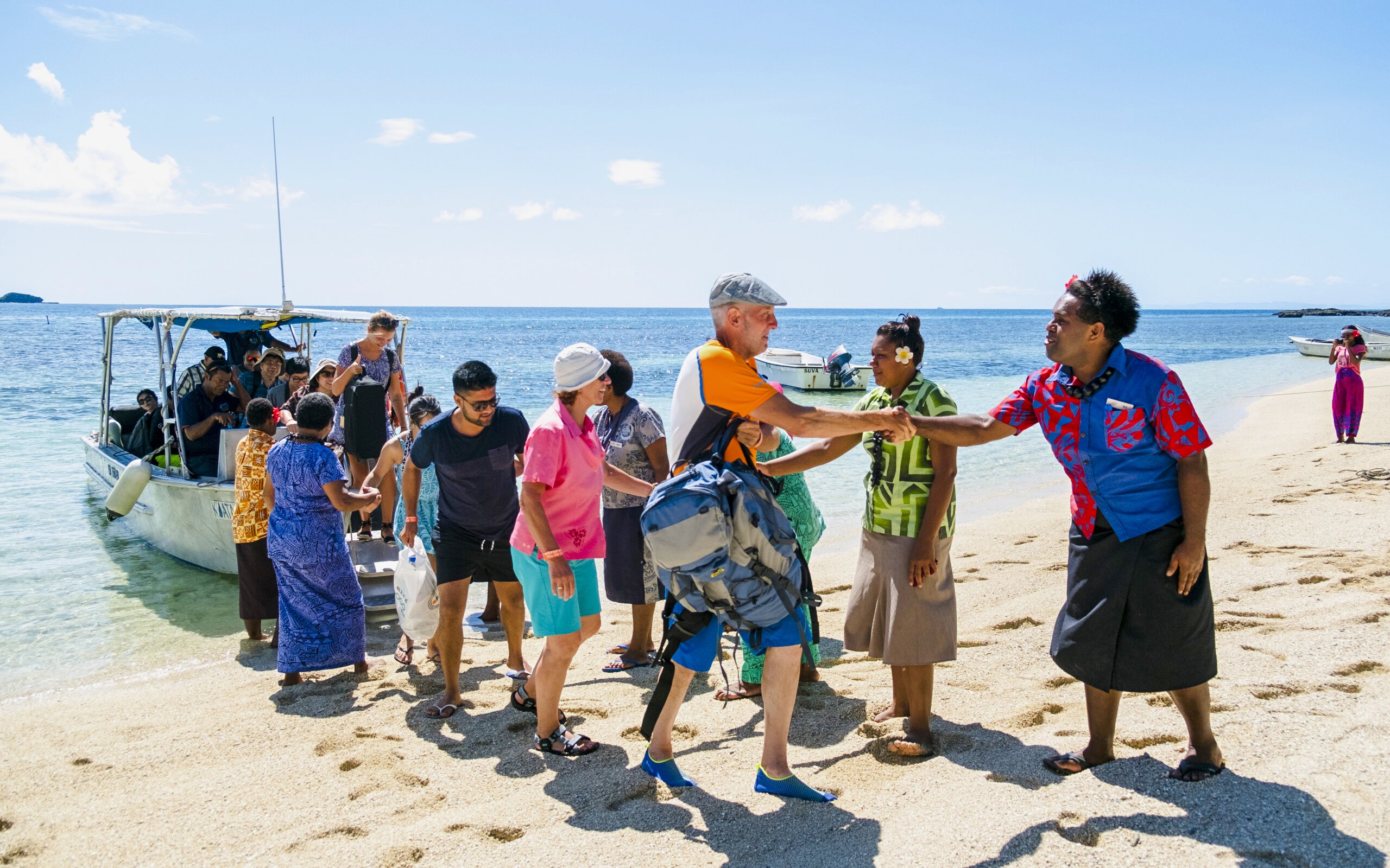 Guests arriving by boat and being greeted at a beach on a Fiji island resort.