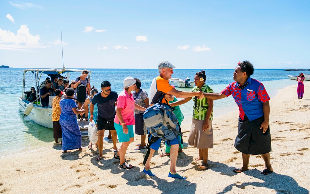 Guests arriving by boat and being greeted at a beach on a Fiji island resort.