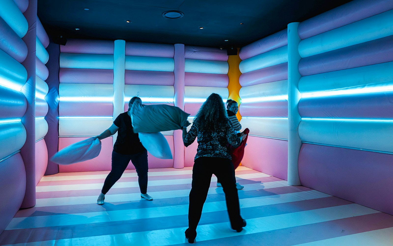 Visitors engaging in a pillow fight at Cushion Clash, Dopamine Land.