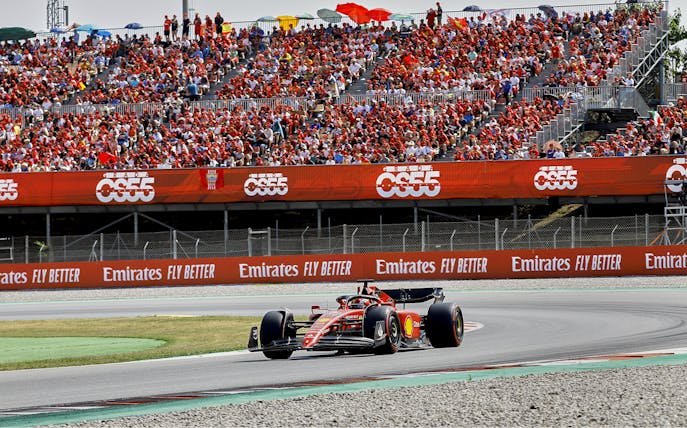Race car on Barcelona F1 track with spectators during Grand Prix.