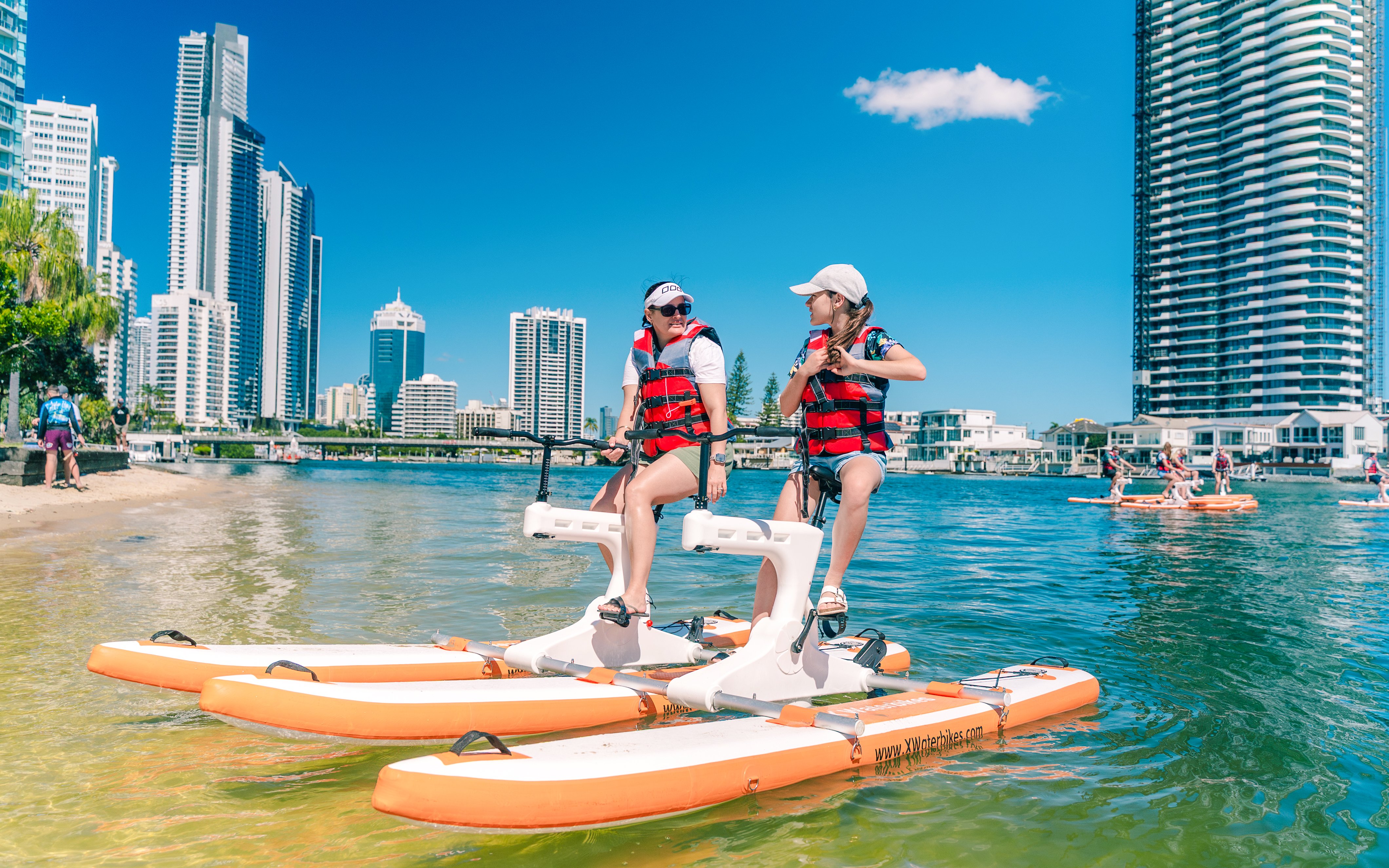 Tourists riding waterbikes on the Gold Coast with city skyline in the background.