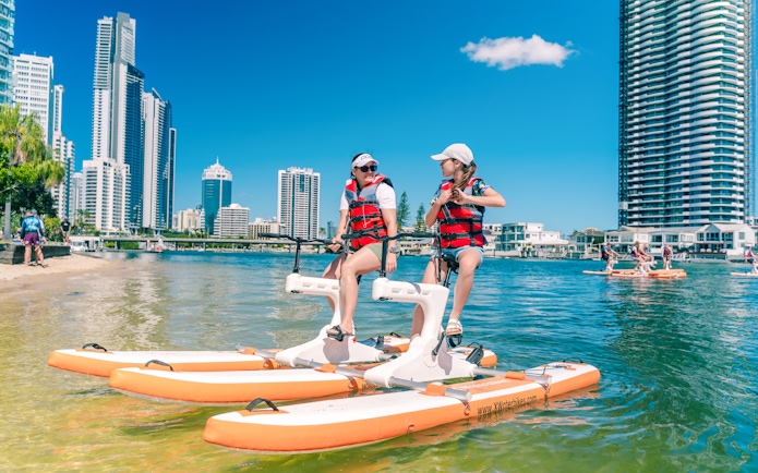 Tourists riding waterbikes on the Gold Coast with city skyline in the background.
