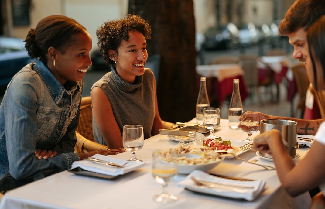 ourists and friends having dinner at restaurant