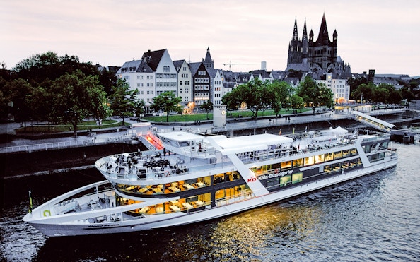 Evening cruise ship on the Rhine River with Cologne Cathedral in the background.