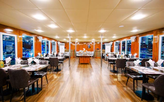 Interior dining area of Alexandra Sea Lounge Dhow Cruise with set tables and large windows.