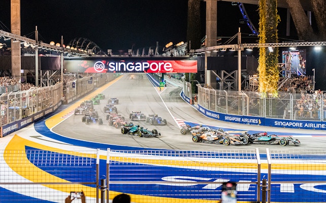 F1 cars racing at Singapore Turn 2 Grandstand during night event.