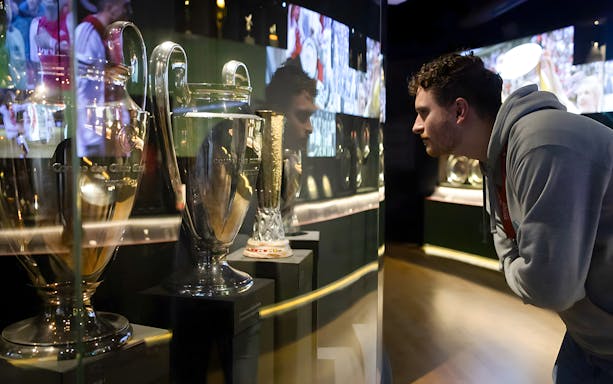 Visitor examining trophies at Johan Cruijff ArenA Classic Tour exhibit.