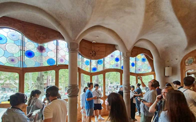 Visitors inside Casa Batlló admiring colorful stained glass windows.