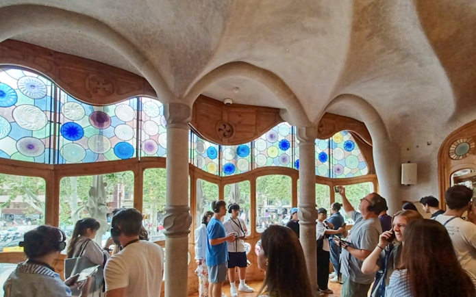 Visitors inside Casa Batlló admiring colorful stained glass windows.