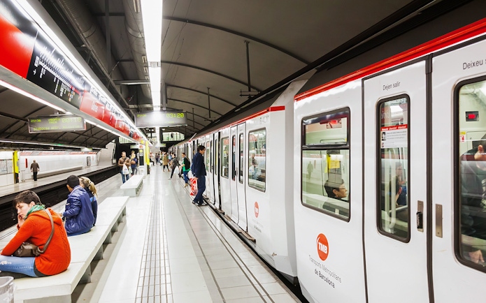 Tourists using Hola Barcelona Travel Card at a Barcelona metro station.