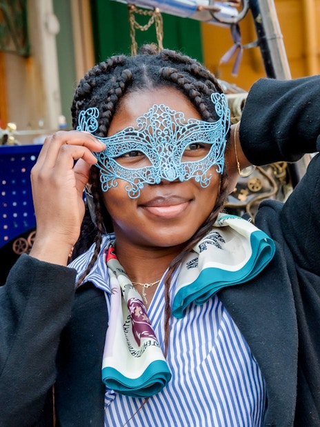 Person holding a decorative mask in a Venetian market.