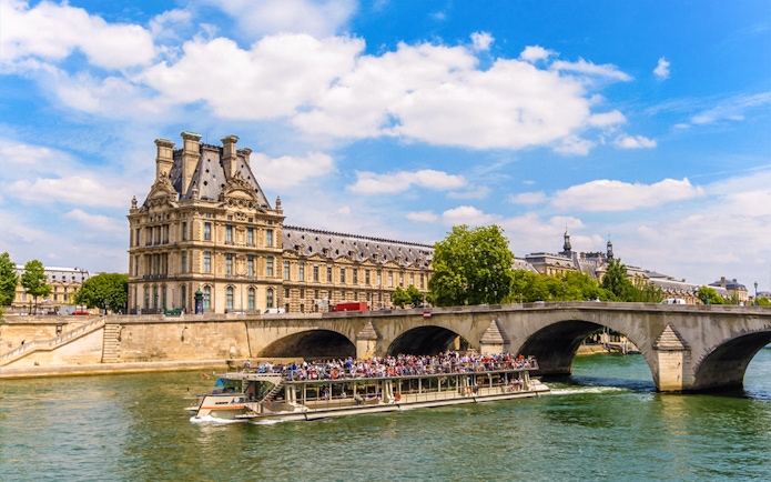 Louvre Museum and Seine River cruise boat in Paris, France.