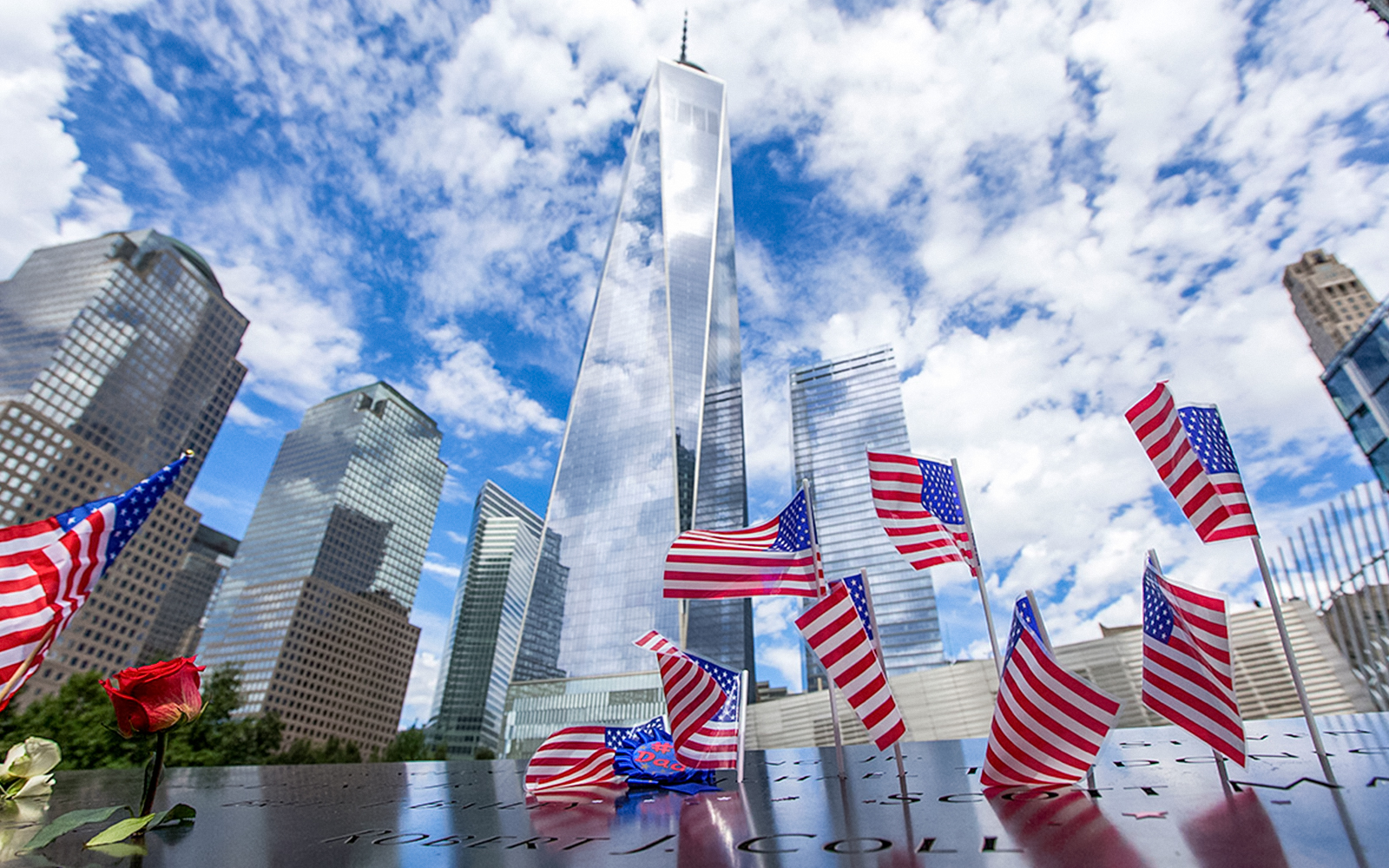 USA flags at 9/11 Memorial with One World Trade Center in New York City.