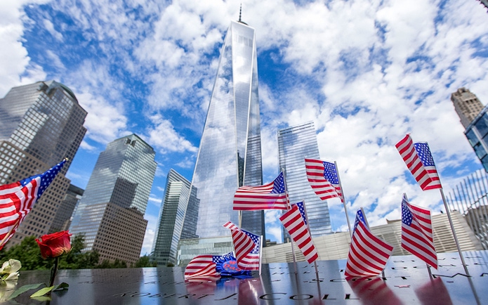 USA flags at 9/11 Memorial with One World Trade Center in New York City.