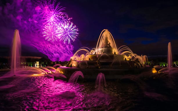 Versailles fountains illuminated with fireworks during night show from Paris.