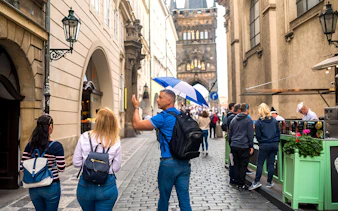 Tour guide leading a group through Prague Old Town near Charles Bridge.