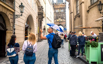 Tour guide leading a group through Prague Old Town near Charles Bridge.