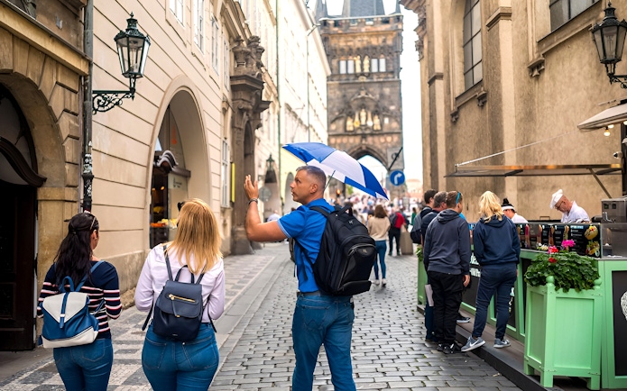 Tour guide leading a group through Prague Old Town near Charles Bridge.