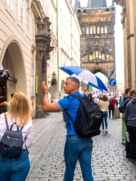 Tour guide leading a group through Prague Old Town near Charles Bridge.
