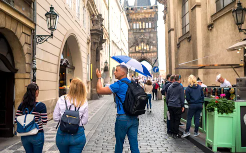 Tour guide leading a group through Prague Old Town near Charles Bridge.