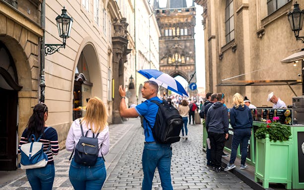 Tour guide leading a group through Prague Old Town near Charles Bridge.